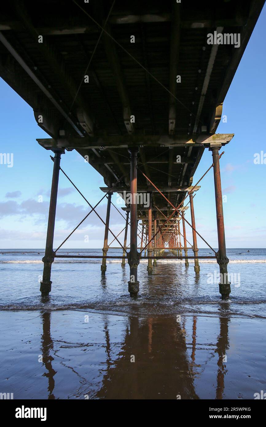 Saltburn Beach, North Yorkshire 2 gennaio 2022 con escursionisti e pagaiatori che sfidano il clima freddo lungo la spiaggia e il molo Foto Stock