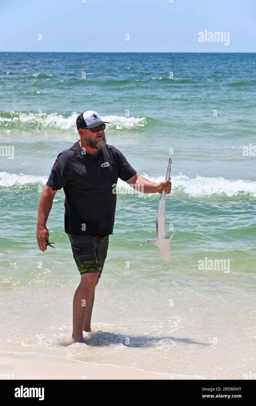 GULF SHORES, al / USA - 3 maggio 2023: Giovane uomo in possesso di uno squalo ha pescato a Gulf Shores Beach sul Golfo del Messico Foto Stock