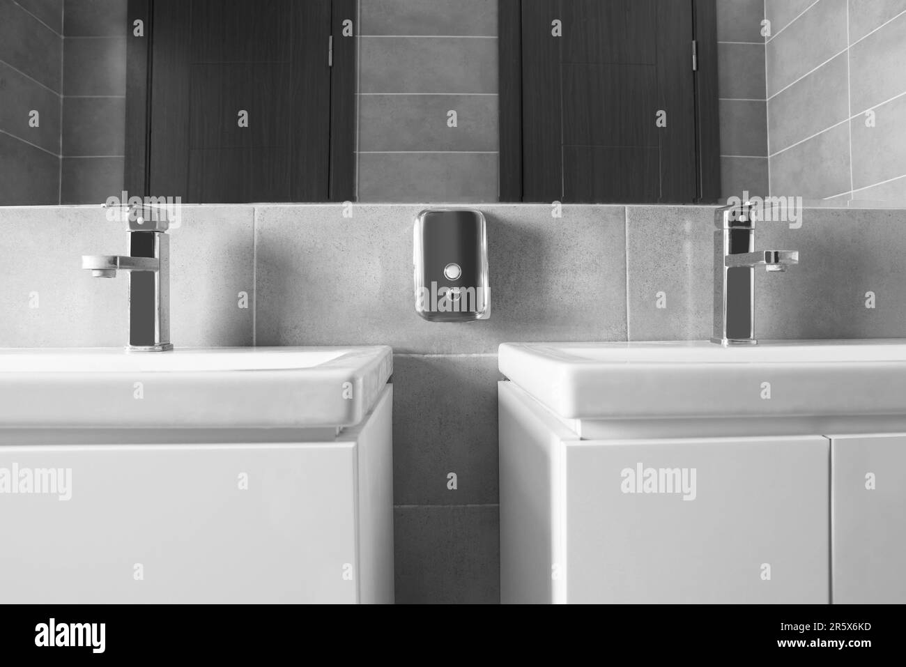 Lavandino bello e pulito vicino allo specchio nel bagno pubblico Foto Stock