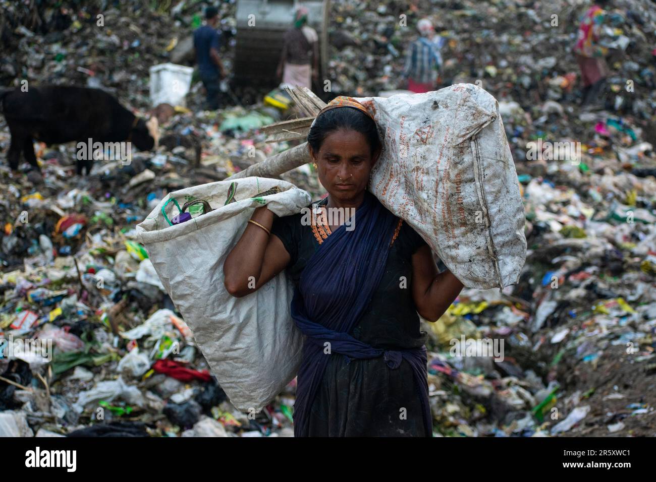 GUWAHATI, INDIA, 4 GIUGNO: Il ragpicker donna trasporta gli articoli riutilizzabili raccolti al luogo di scarico di immondizia di Boragaon, davanti alla Giornata Mondiale dell'ambiente, sopra Foto Stock