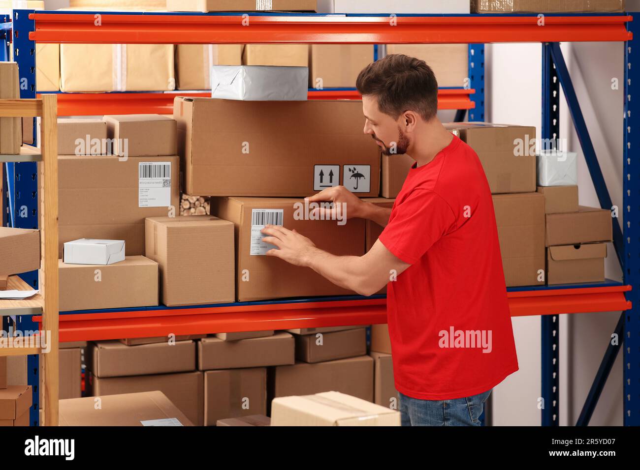 Addetto all'ufficio postale vicino al rack con pacchi all'interno Foto Stock