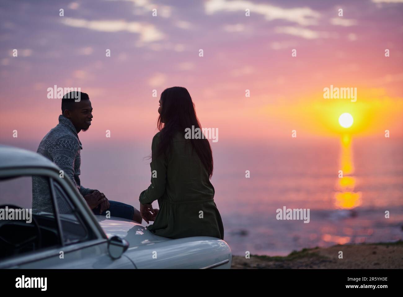 La ho portata qui per porre una domanda speciale. una giovane coppia che fa una sosta in spiaggia mentre fuori in viaggio. Foto Stock