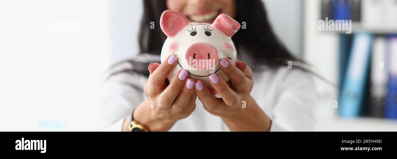 Donna d'affari sorridente che tiene bianco rosa piggy banca Foto Stock