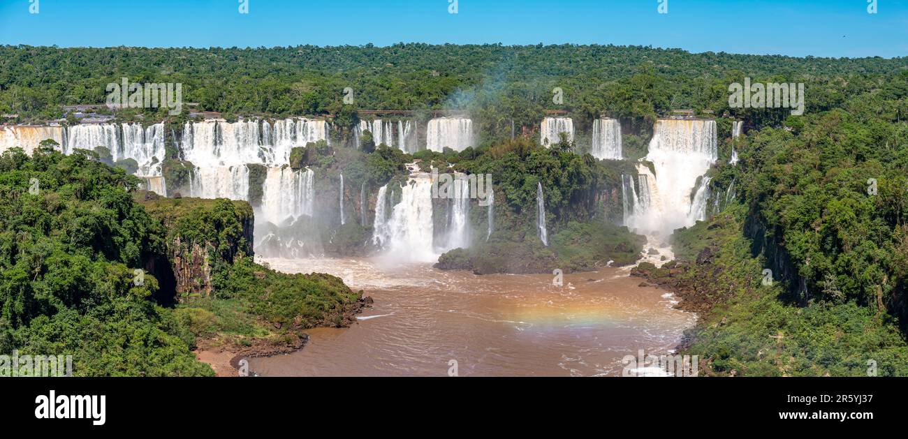 Vista panoramica della spettacolare cascata delle Cascate di Iguazu al sole e sul fiume marrone, Argentina Foto Stock