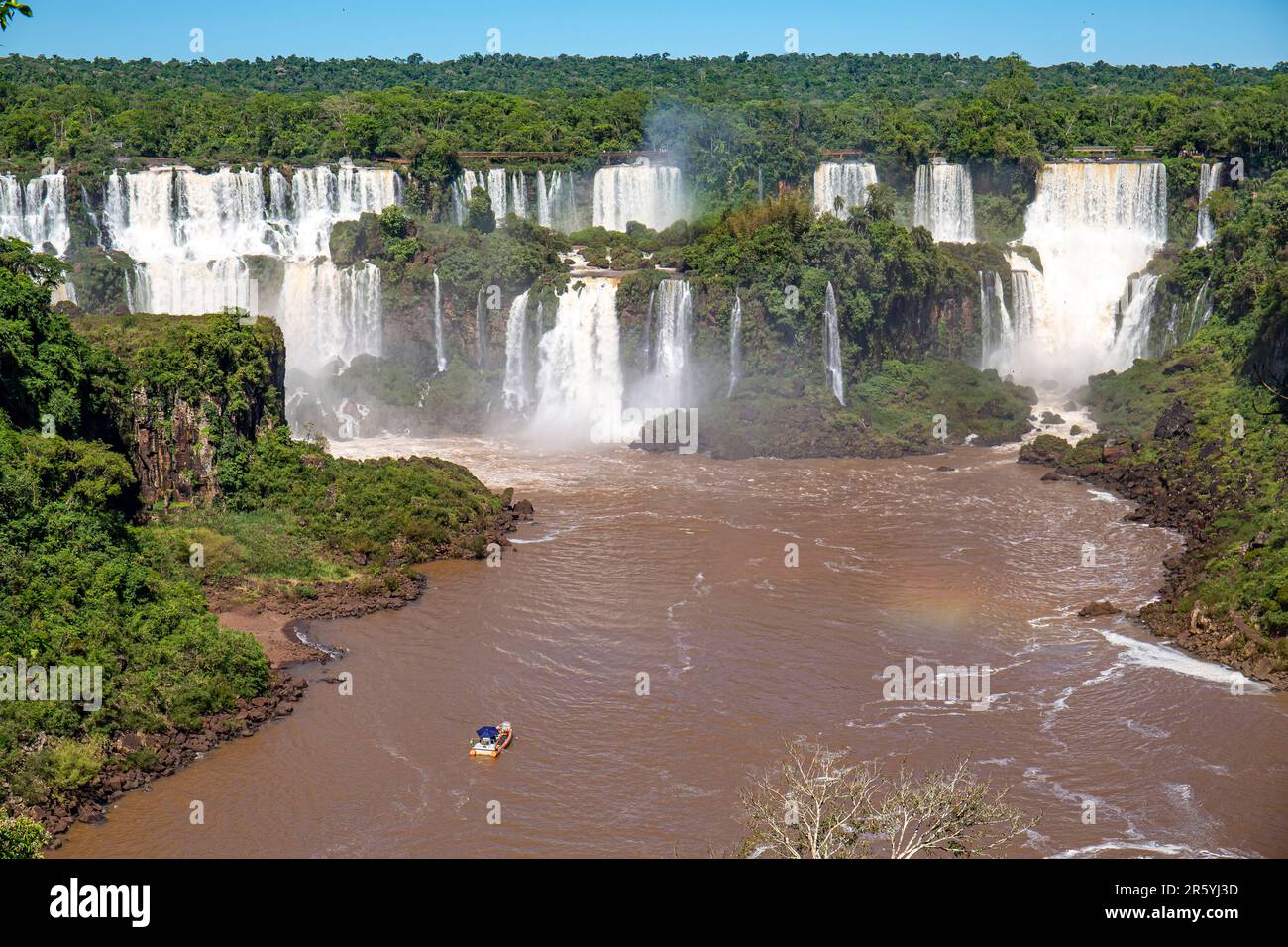 Vista della spettacolare cascata delle Cascate di Iguazu sotto il sole e il fiume marrone, Argentina Foto Stock