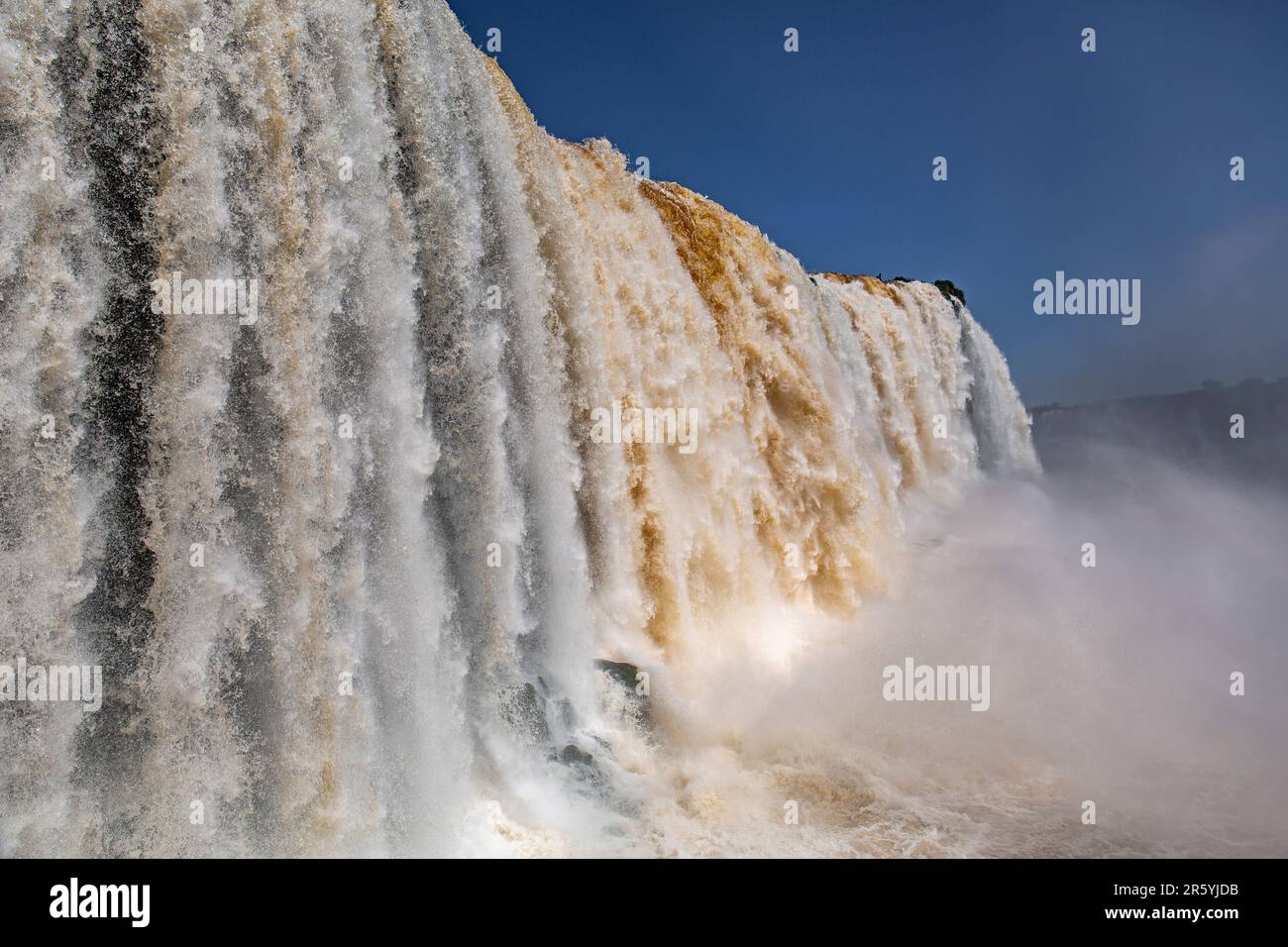 Vista ravvicinata delle potenti cascate di Iguazu in diversi colori e con il cielo blu Foto Stock