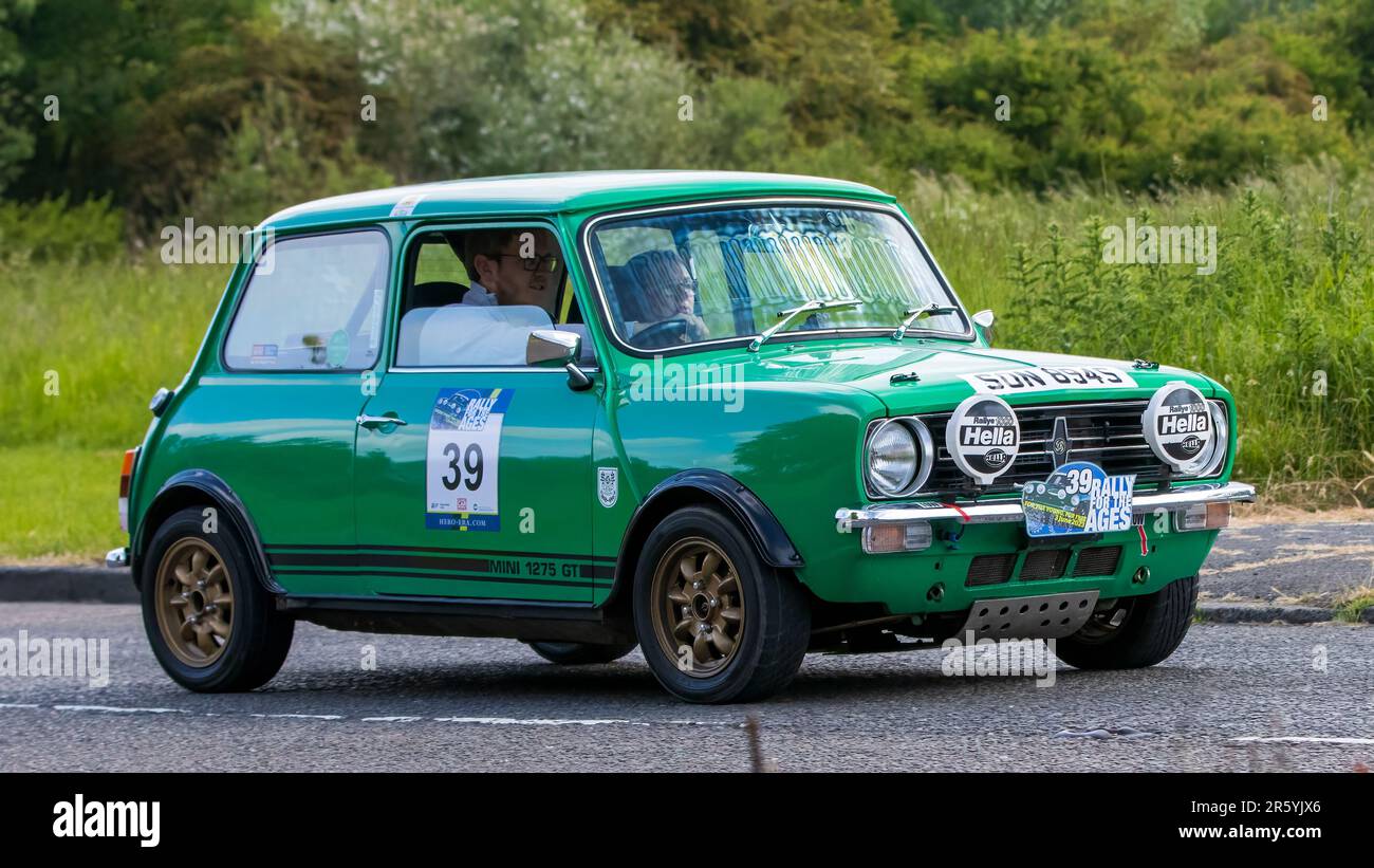 Stony Stratford, Regno Unito - Giugno 4th 2023: 1977 mini 1275 GT auto classica verde in viaggio su una strada di campagna inglese. Foto Stock