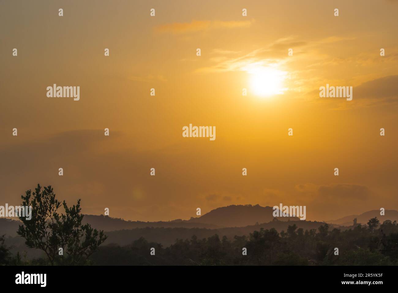 Una tranquilla scena di bellezza nella natura, con un suggestivo cielo arancione che riflette la montagna e gli alberi nebbosi. Un retrogusto perfetto al crepuscolo come il s Foto Stock