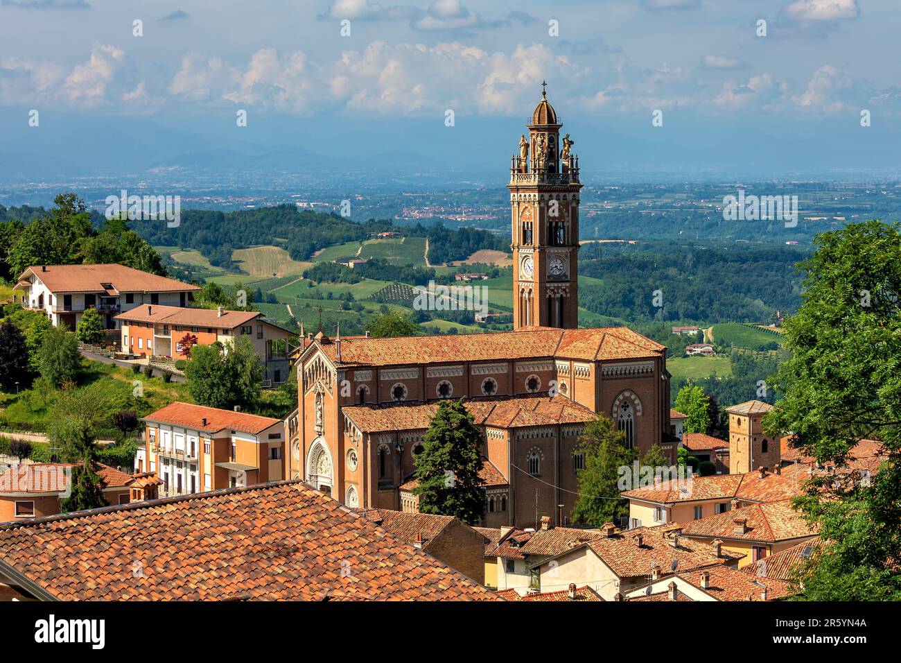 Vista della chiesa con alto campanile tra vecchie case con tetti rossi nel piccolo paese di Monforte d'Alba in Piemonte. Foto Stock