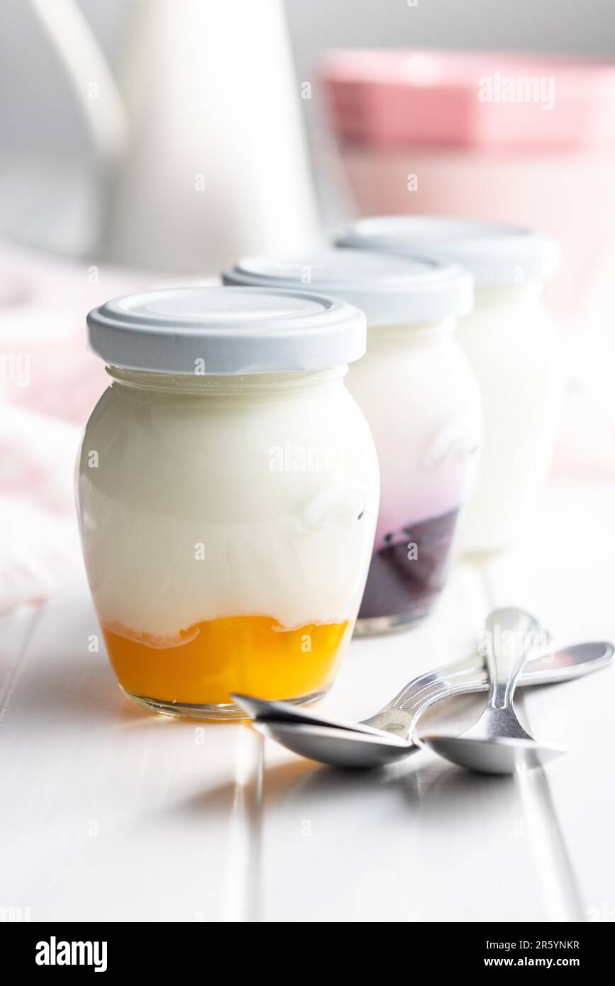 Yogurt bianco e fruttato in vaso sul tavolo bianco. Foto Stock