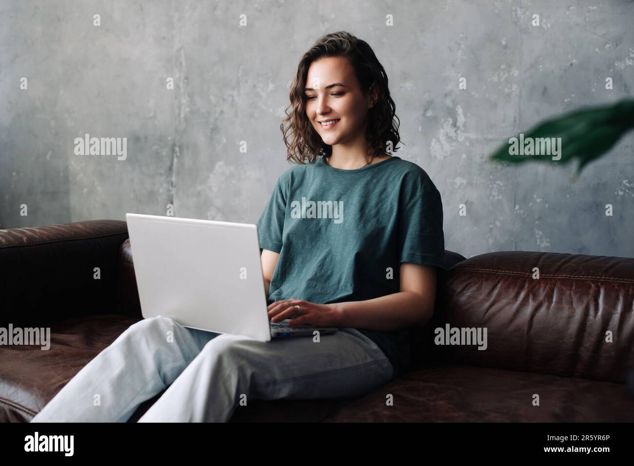 Produttività e indipendenza: La giovane donna si impegna nel lavoro e nello studio a distanza, utilizzando il notebook nel comfort di casa. Abbracciare i benefici di freela Foto Stock