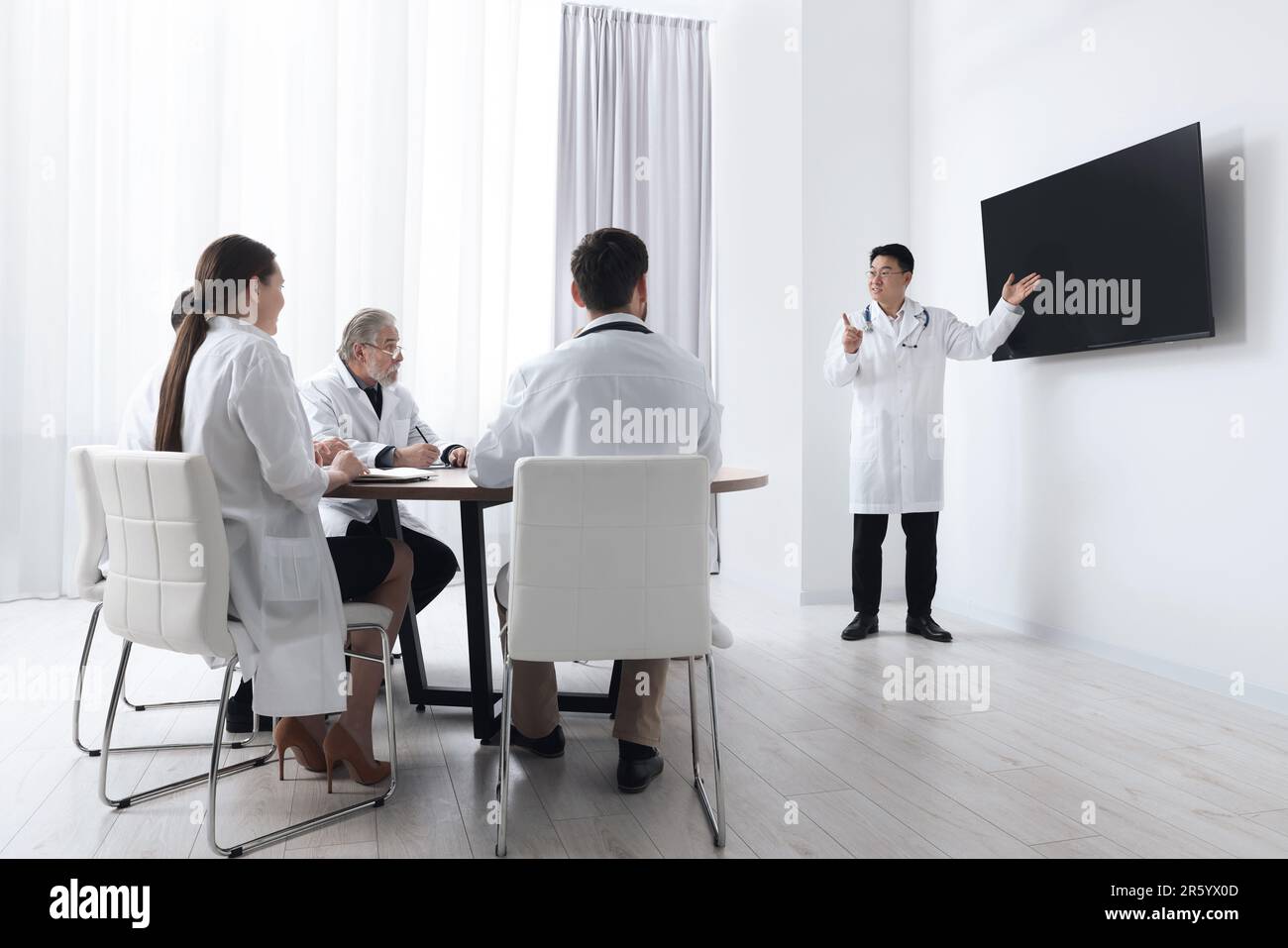 Team di medici che ascoltano il rapporto degli altoparlanti vicino allo  schermo tv nella sala riunioni. Conferenza medica Foto stock - Alamy