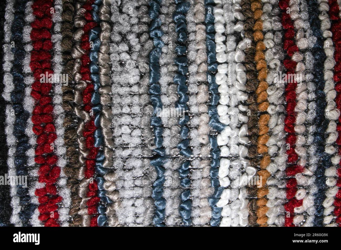 Primo piano di un tappeto a righe multicolore con spesse passanti in tessuto. Presenta un vivace mix di tonalità di rosso, blu, grigio, marrone e bianco. Perfetto per desi Foto Stock