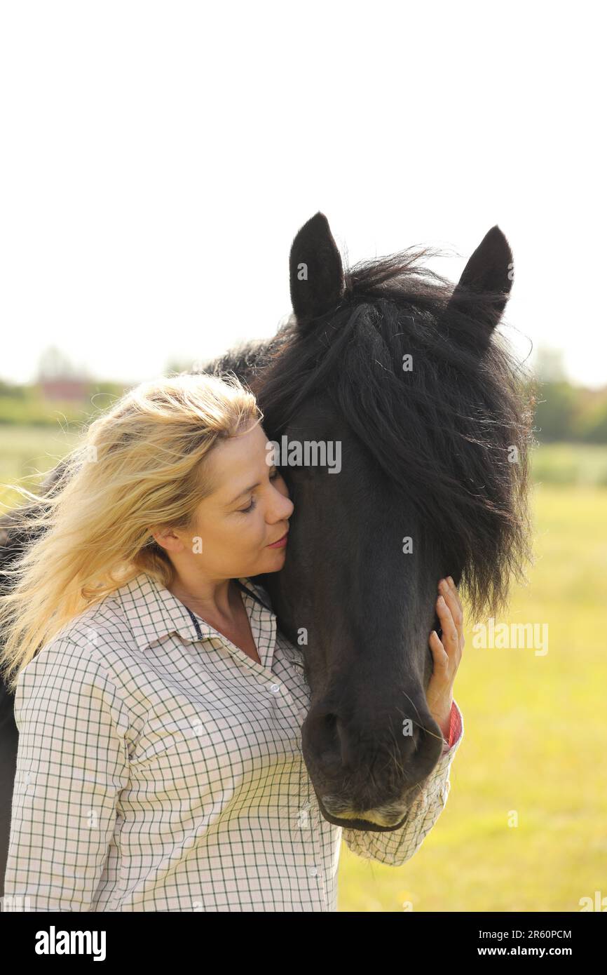 Una donna bionda che bacia un pony caduto nero Foto Stock