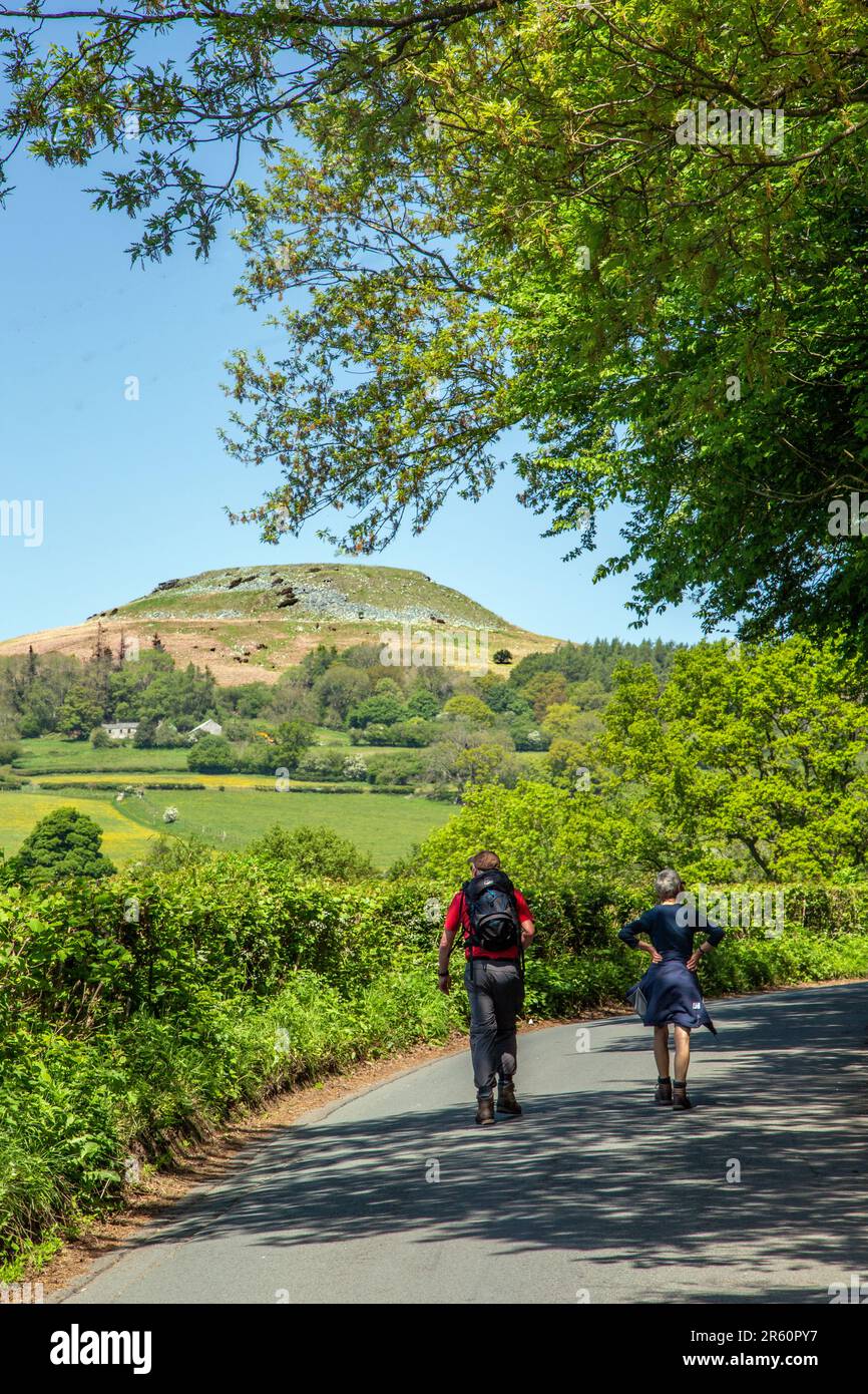 Persone che camminano lungo le strade di campagna nella campagna del Galles del Sud a Crickhowell Powys con vista sul punto di riferimento locale di Table Mountain Foto Stock