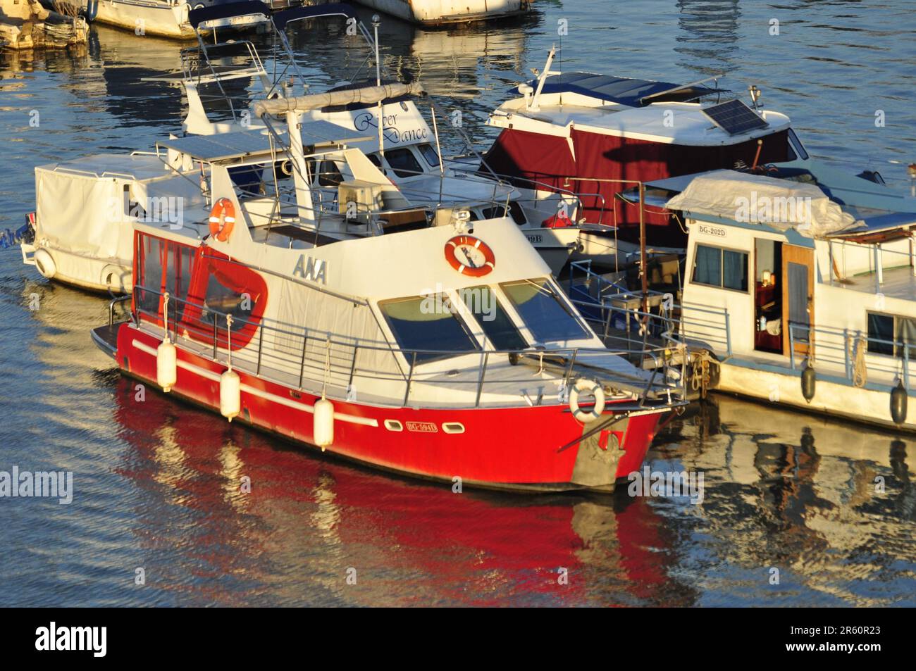 Barca bianca e rossa in marina con riflesso Foto Stock