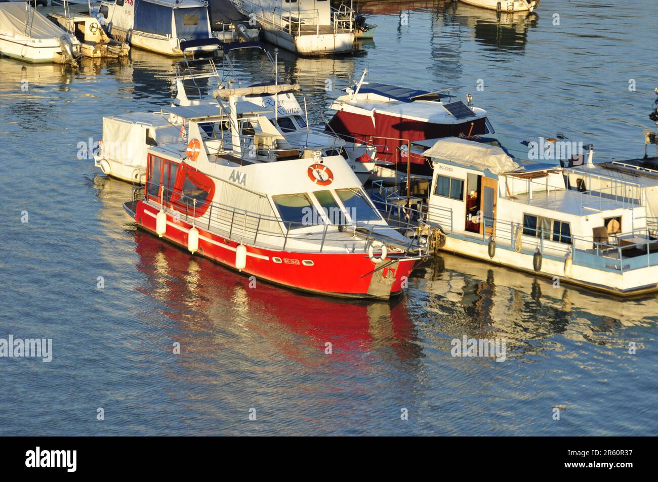 Barca bianca e rossa in marina con riflesso Foto Stock