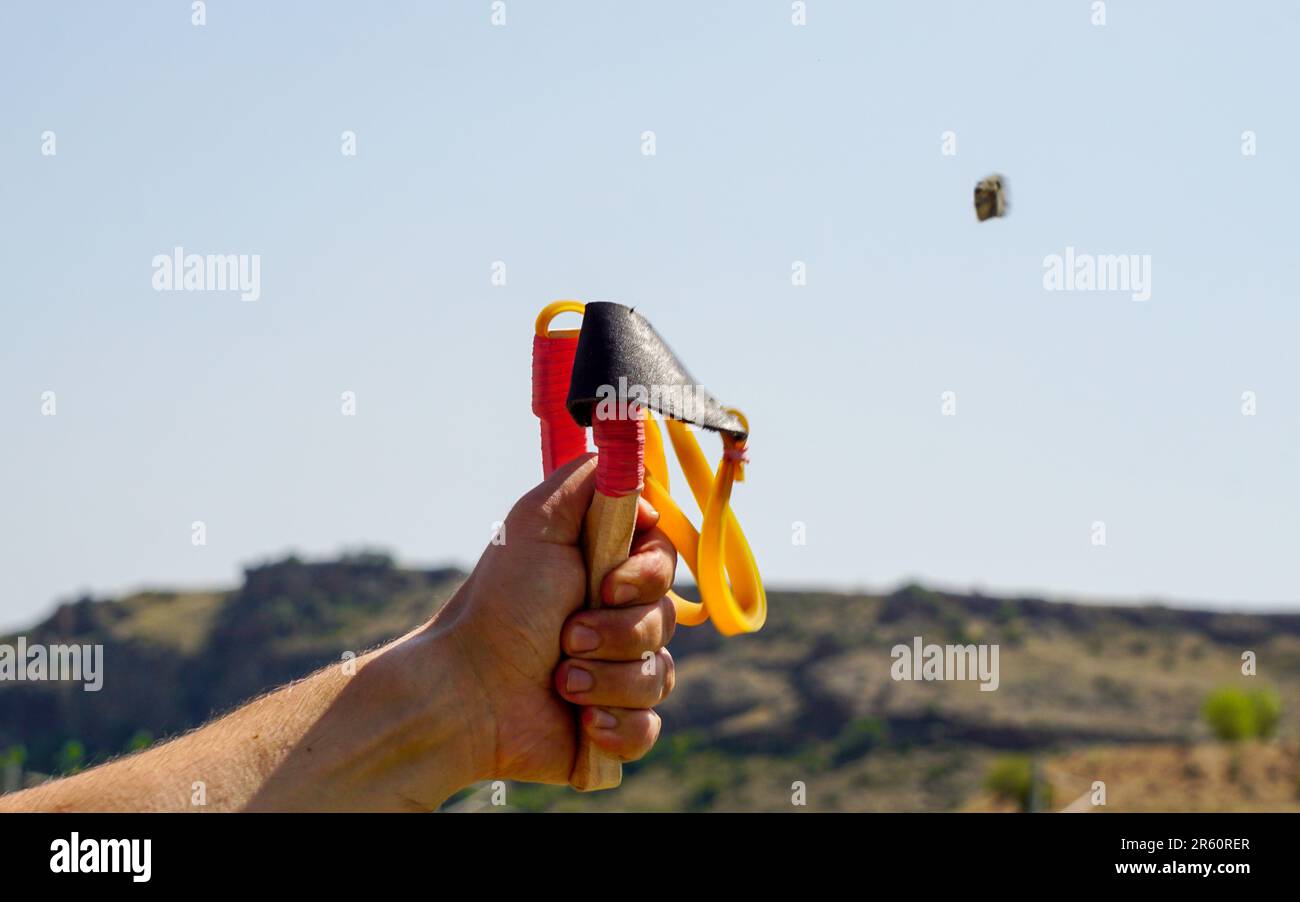 Uomo che usa il lanciatore di lancia che lancia rocce e divertimento naturale Foto Stock