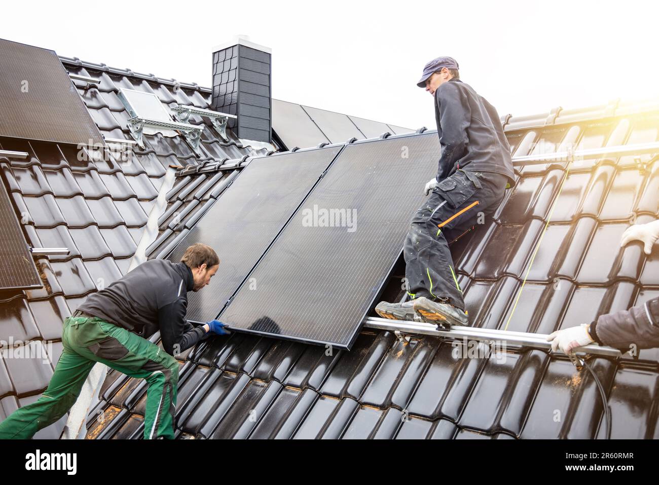 Commercianti che installano pannelli solari sul tetto di una casa Foto Stock