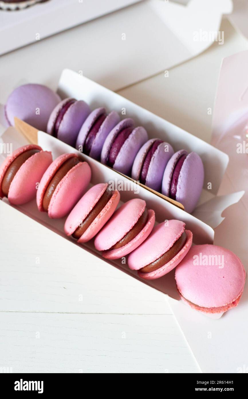 Macaron rosa e viola con ripieno di cioccolato in confezione regalo. L'idea di un regalo dolce carino per una ragazza per una festa Foto Stock