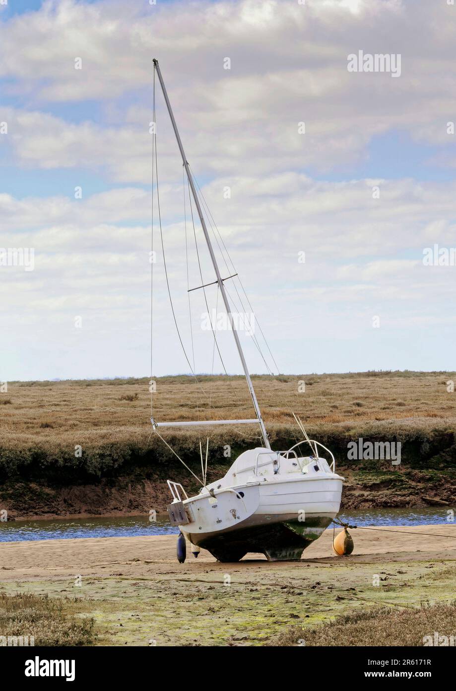 Bassa marea lungo New Cut a Blakeney, North Norfolk, con le barche lasciate in piedi sul fango in attesa della successiva marea di alluvione. Foto Stock