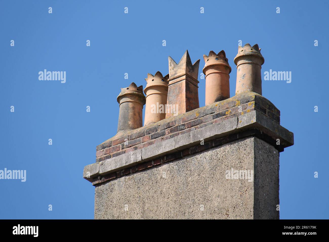 Cinque tradizionali Chimney Pot di terracotta su uno stack di mattoni. Foto Stock