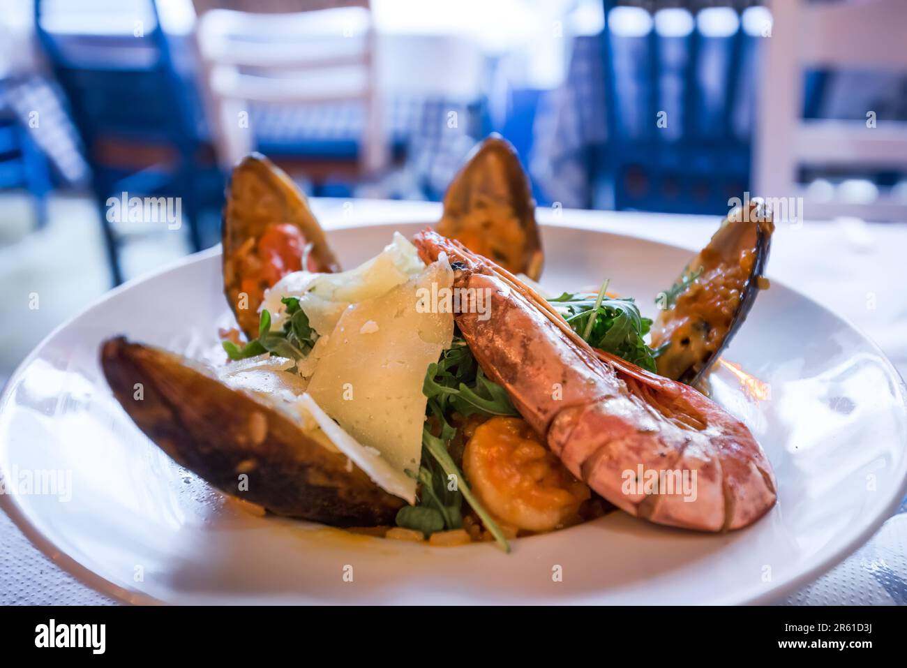 Classico risotto a base di pesce, con frutti di mare freschi e erbe aromatiche e spezie mediterranee. Cucina greca, taverna sfondo. Foto Stock