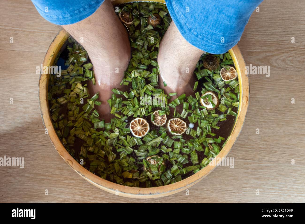 Un uomo si bagna i piedi in un bagno alle erbe Foto Stock