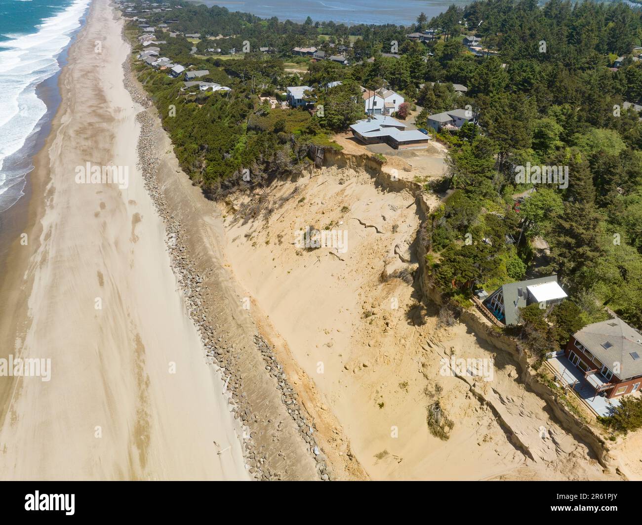 Solo uno scivolo di sabbia rimane dopo che le case sul lungomare sono state distrutte con più in pericolo di distruzione a causa dell'erosione costiera a Glen Eden Beach, Oregon. Riprap - una costruzione di grandi rocce - protectscontro l'aumento del livello del mare sulla costa dell'Oregon dell'Oceano Pacifico. La misura temporanea può costare oltre $$1000 per piede lineare ed è sopportata in questo caso dal proprietario di abitazione. Foto Stock