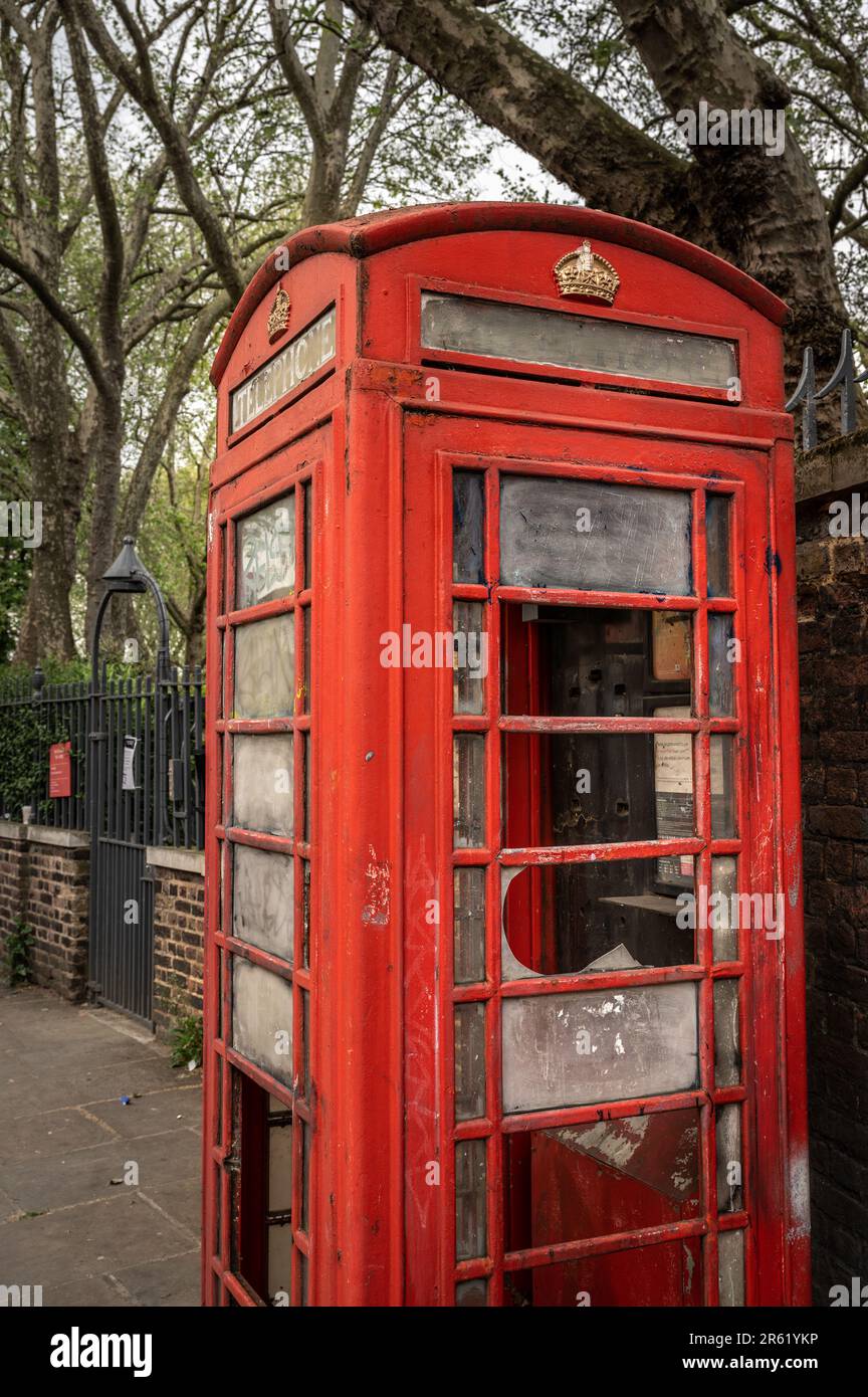 Londra, Regno Unito: Una vecchia cassetta telefonica su Kingsland Road a Hoxton, Londra. Questo chiosco telefonico rosso è stato vandalizzato e il vetro è rotto. Foto Stock