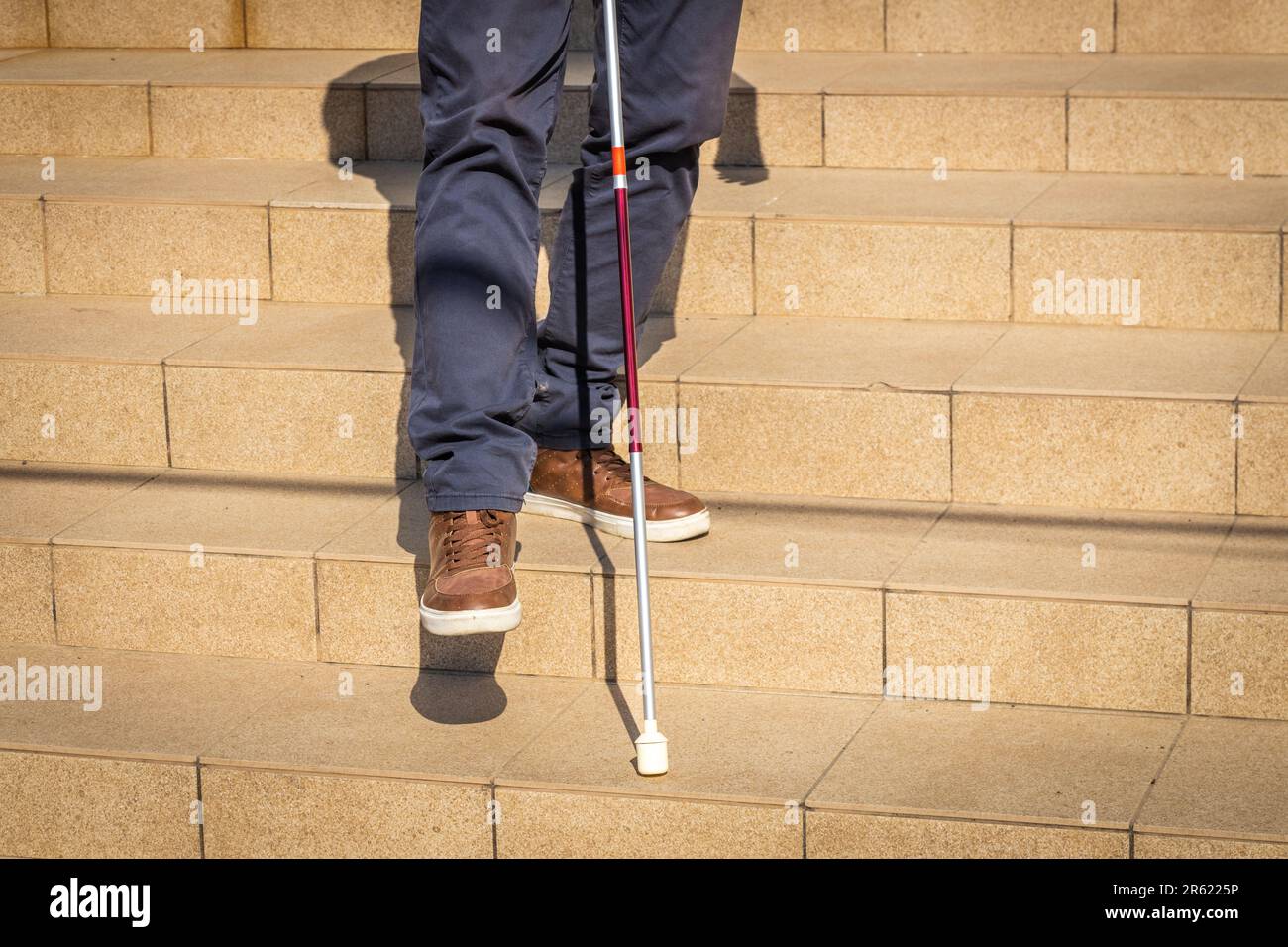 Una persona cieca cerca di scendere le scale aiutandosi con un bastone, problemi di disabilità, concetto, facilità di accesso, strategia per l'uguaglianza per le persone Foto Stock