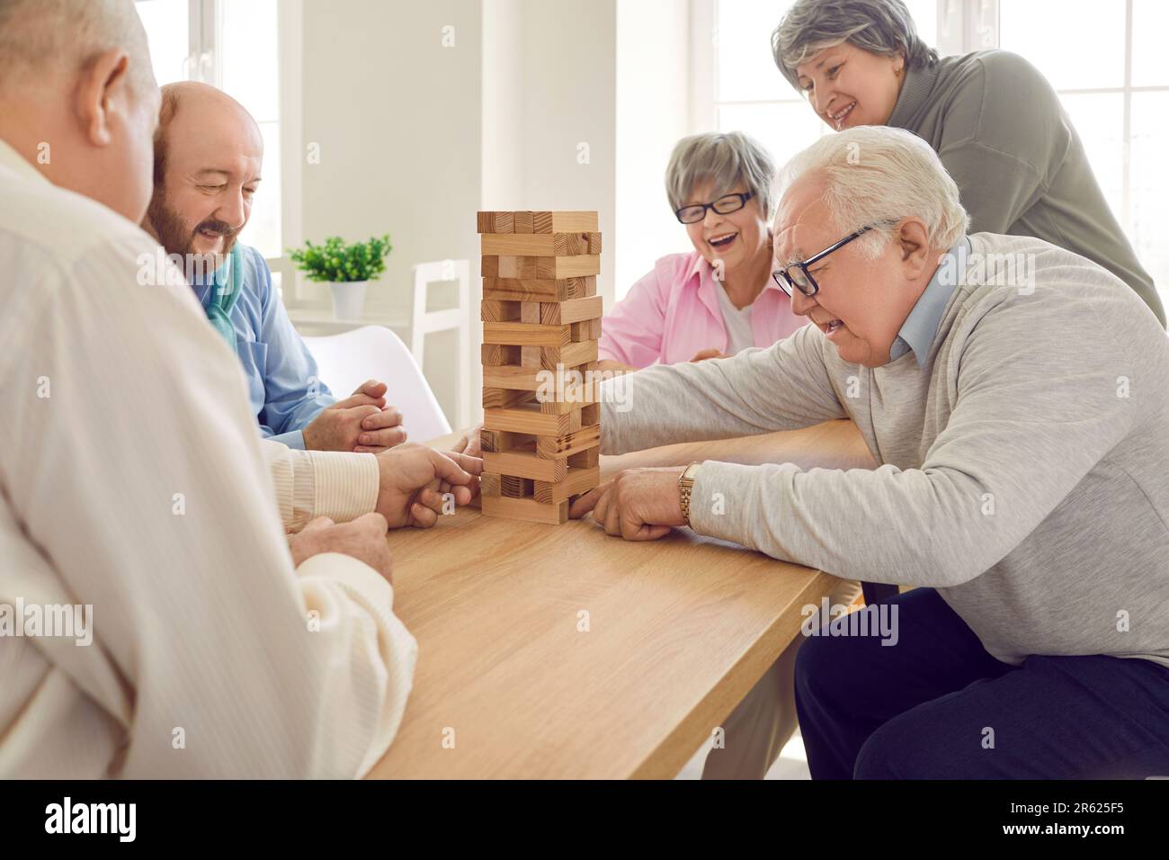 Gruppo di persone anziane felici che giocano con il gioco da tavolo torre di legno in casa di riposo Foto Stock