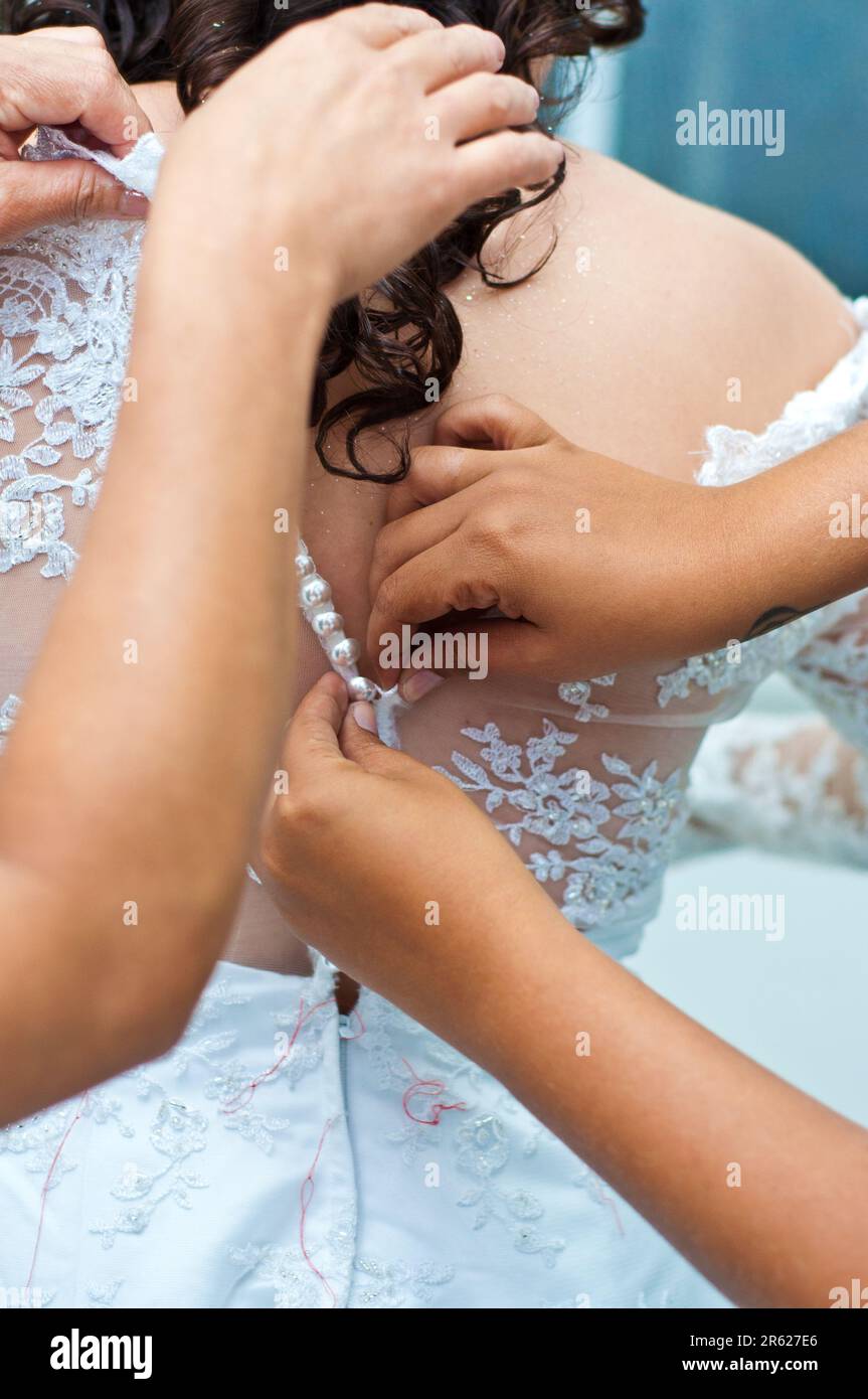 Mani che chiudono un abito da sposa. Preparare la sposa per il matrimonio. Foto Stock