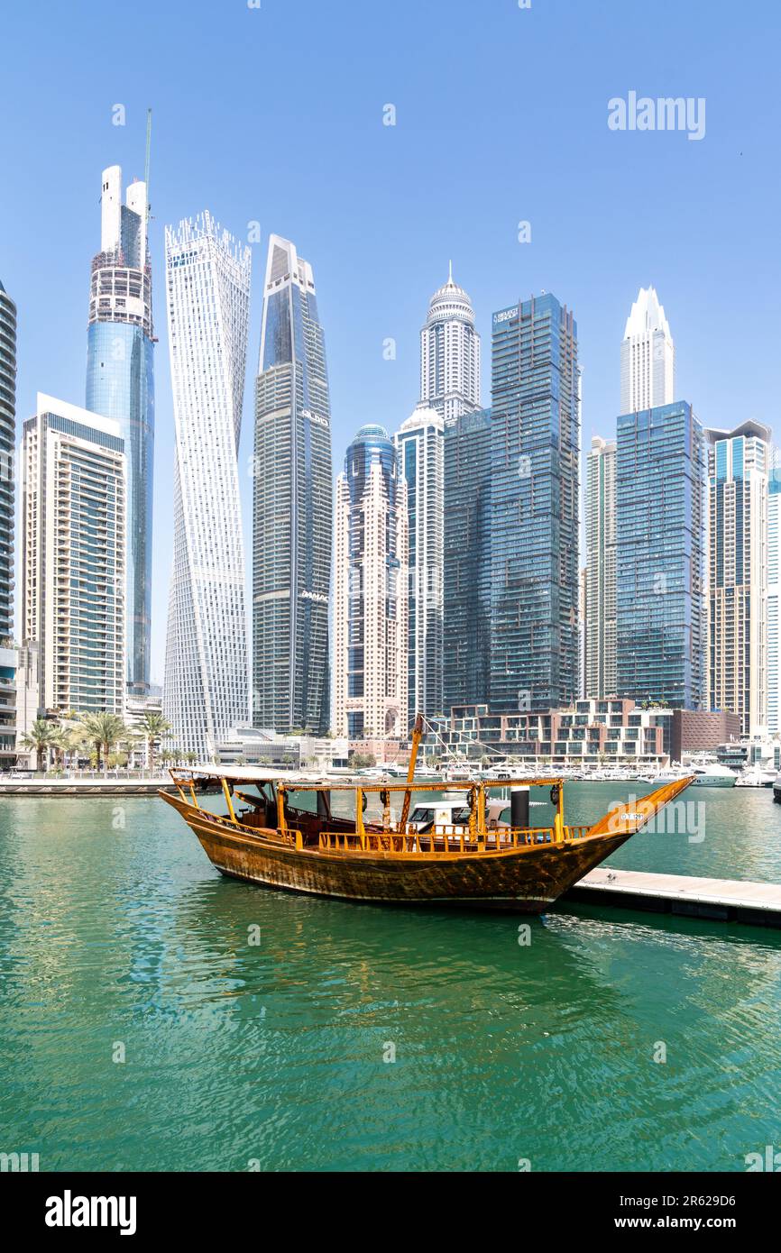 Dubai, Emirati Arabi Uniti - 12 marzo 2023: Vista dei grattacieli di Dubai e delle barche tradizionali mentre si cammina a Dubai Marina durante una giornata di sole Foto Stock