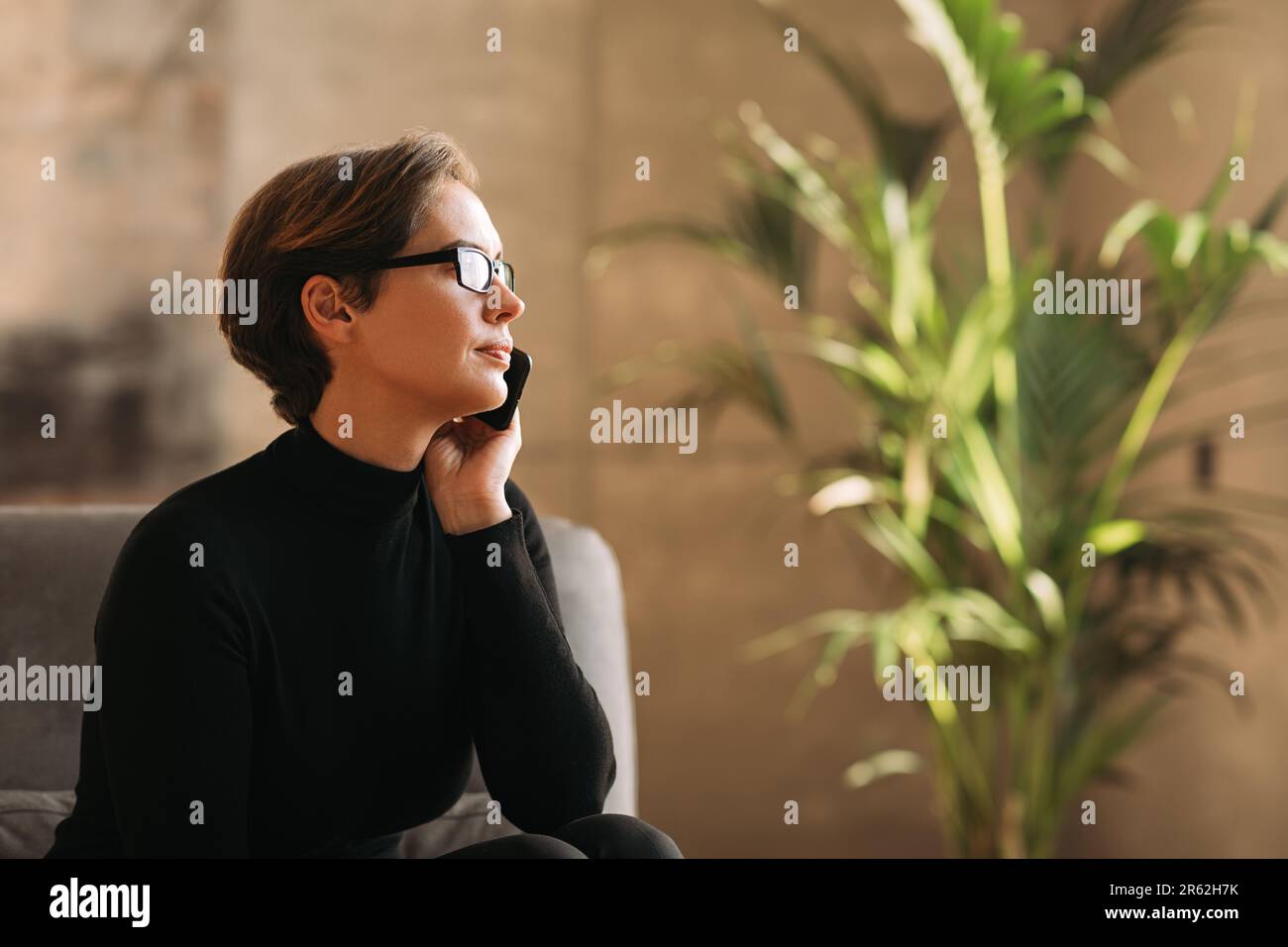 Vista laterale di una donna d'affari con capelli corti che parla su un telefono cellulare Foto Stock