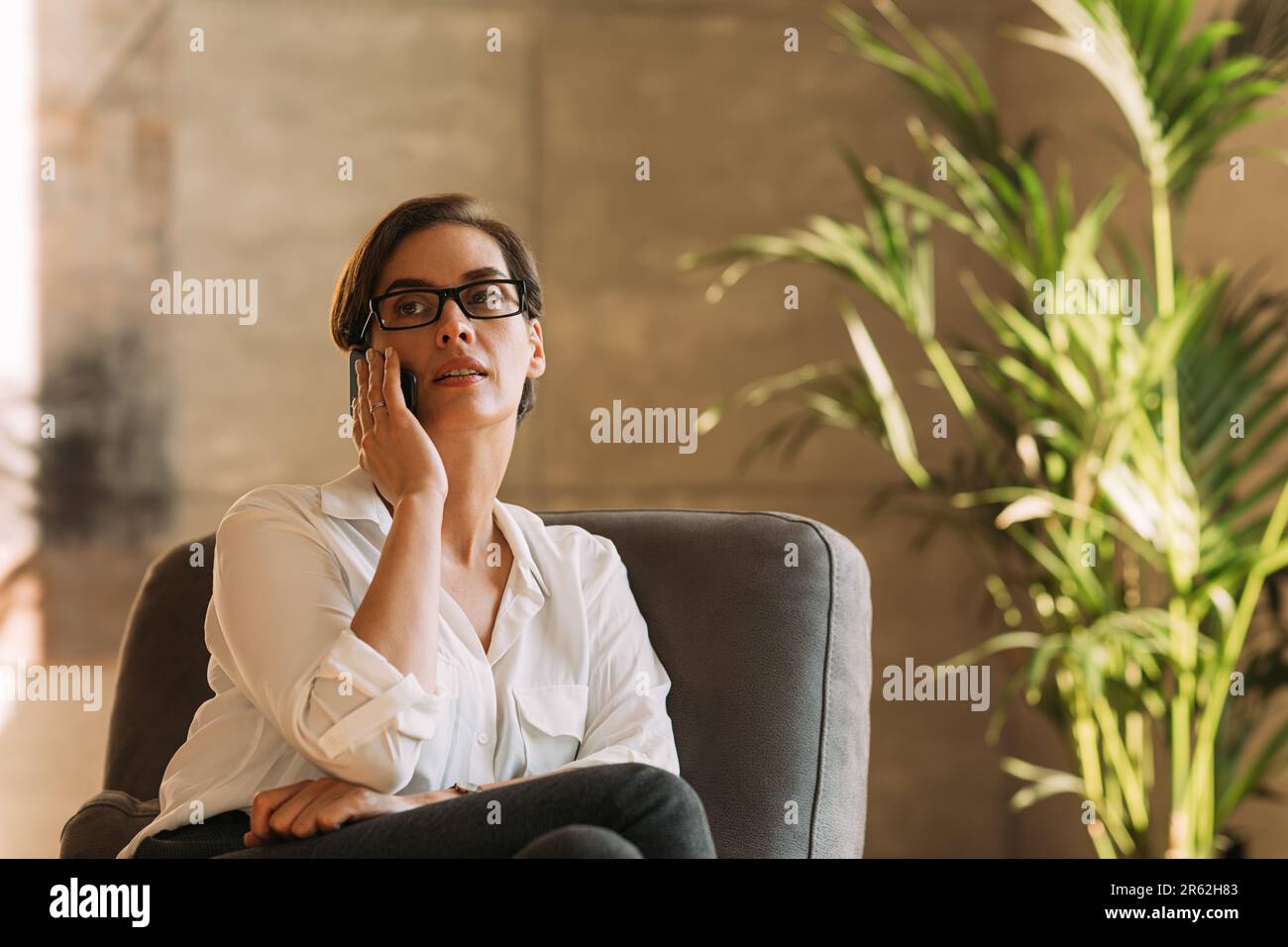 Donna d'affari di mezza età in occhiali che parlano sul telefono cellulare Foto Stock