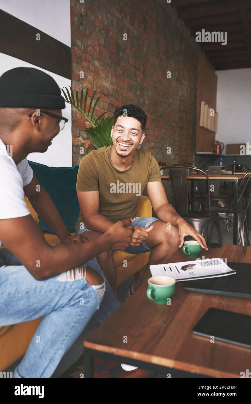 Una riunione d'affari non sarebbe la stessa senza un buon caffè. due uomini ridono mentre si siedono insieme in una caffetteria. Foto Stock