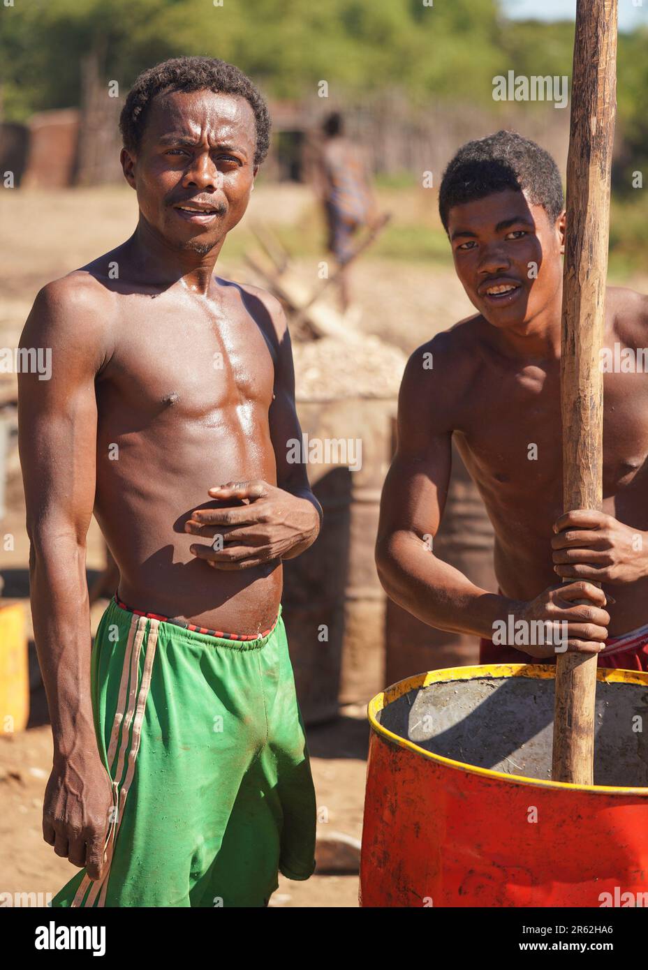 Andranovory, Madagascar - 30 aprile 2019: Due uomini malgasci sconosciuti che estraggono il succo dai frutti in barile grande con il palo di legno - questo deve essere usato Foto Stock