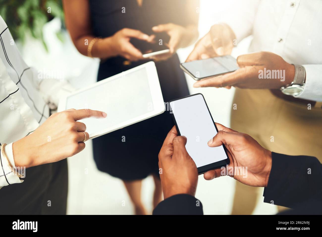 I loro dispositivi intelligenti assicurano che tutto sia sulla stessa pagina. Primo piano di un gruppo di uomini d'affari che utilizzano i loro dispositivi digitali in sincronia in un Foto Stock
