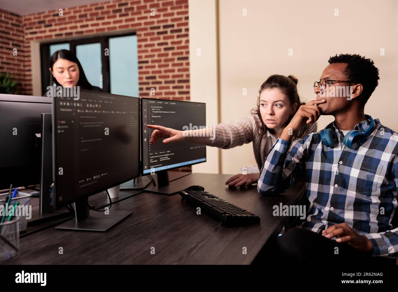 Sviluppatore di software che chiede aiuto al codificatore con codice html, puntando allo script del database sulla finestra del terminale. Team di ingegneri di programmazione che lavorano al programma di sviluppo di app nella sala dati. Foto Stock