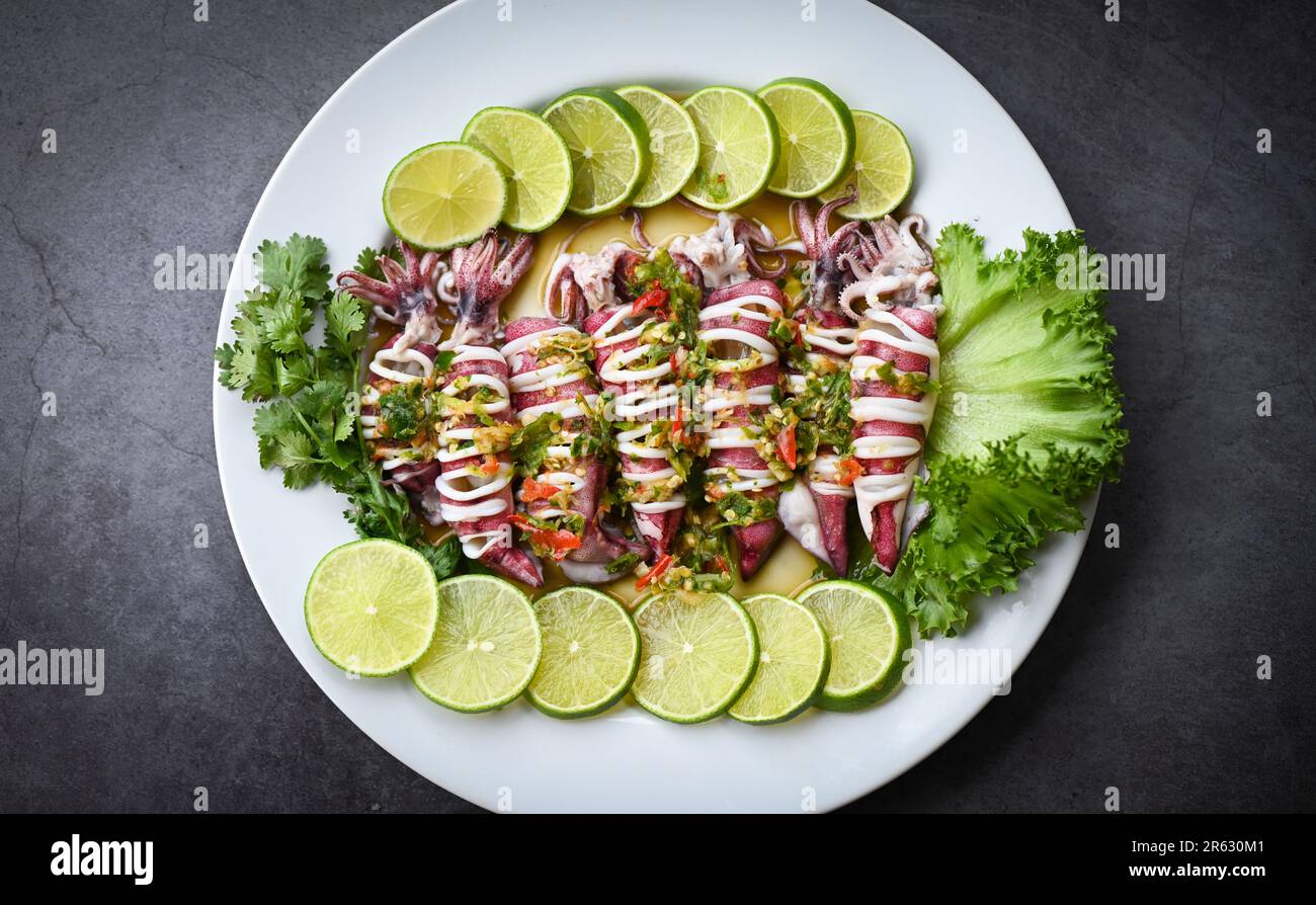 Calamari al vapore con peperoncino piccante al limone e calamari al limone al vapore con lime, piatti di pesce thailandesi con erbe e spezie - vista dall'alto Foto Stock