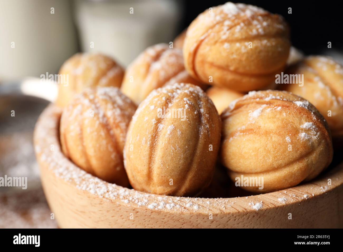 Deliziosi biscotti a forma di noci con zucchero a velo in ciotola di legno, primo piano Foto Stock