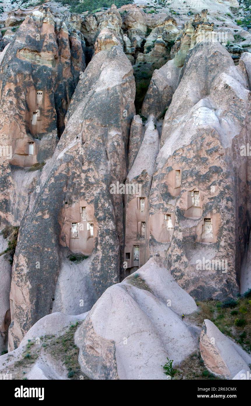 Ex case scavate nella roccia di formazioni rocciose vulcaniche conosciute come camini delle fate a Cavusin, nella regione della Cappadocia di Turkiye. Foto Stock