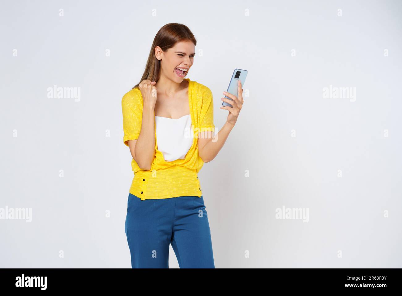 Donna eccitata che festeggia con il telefono cellulare isolato su sfondo bianco. Foto Stock
