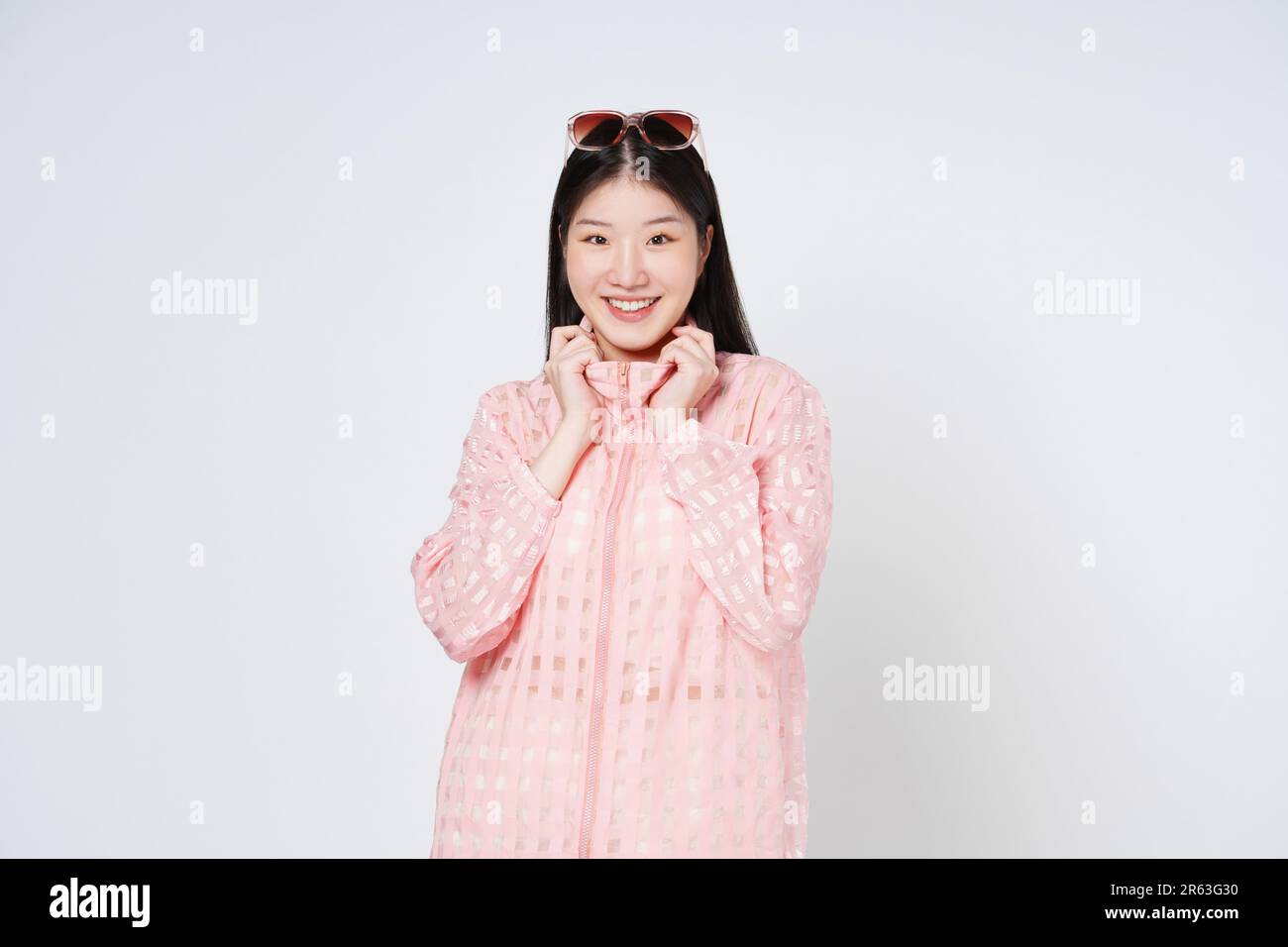Felice giovane donna tiene il colletto di vestiti rosa da due mani isolato su sfondo bianco. Foto Stock
