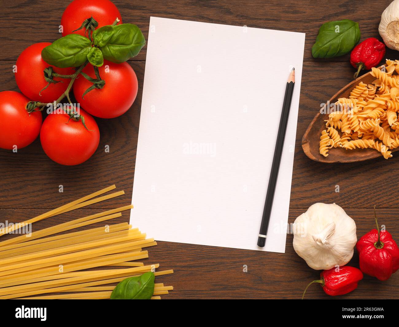 La pasta o il cibo italiano concetto lo sfondo con un vuoto di foglio di carta e matita su un tavolo di legno Foto Stock