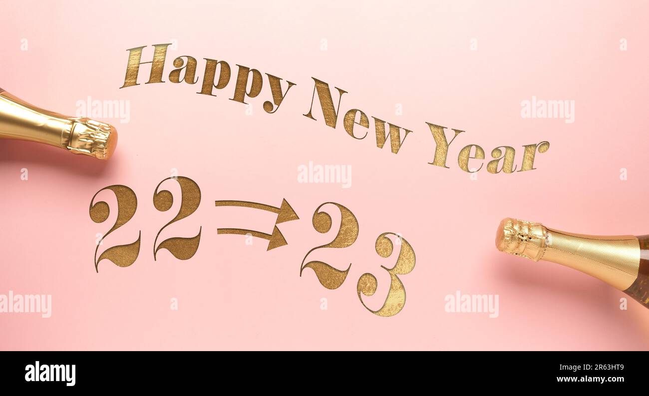 Le parole Felice anno nuovo con 2023 e 2023 dorati su sfondo rosa con due bottiglie di champagne, auguri di Capodanno, sfondo festivo Foto Stock