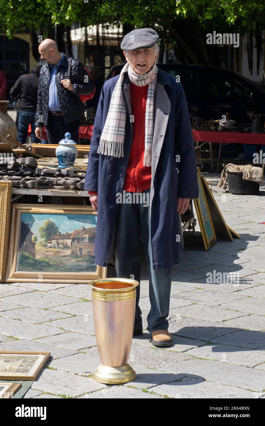 Palermo Domenica mercato delle pulci Vecchio in cappello piatto e cappotto guardando vaso di ottone grande Foto Stock