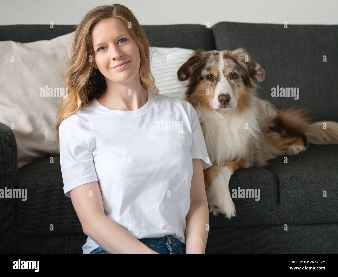 Donna con Australian Shepherd Indoor Couch Mockup Shirt seduta sorridente Foto Stock