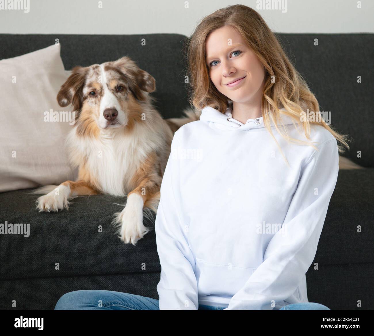 Donna con Australian Shepherd Indoor Couch Mockup Shirt seduta sorridente Foto Stock